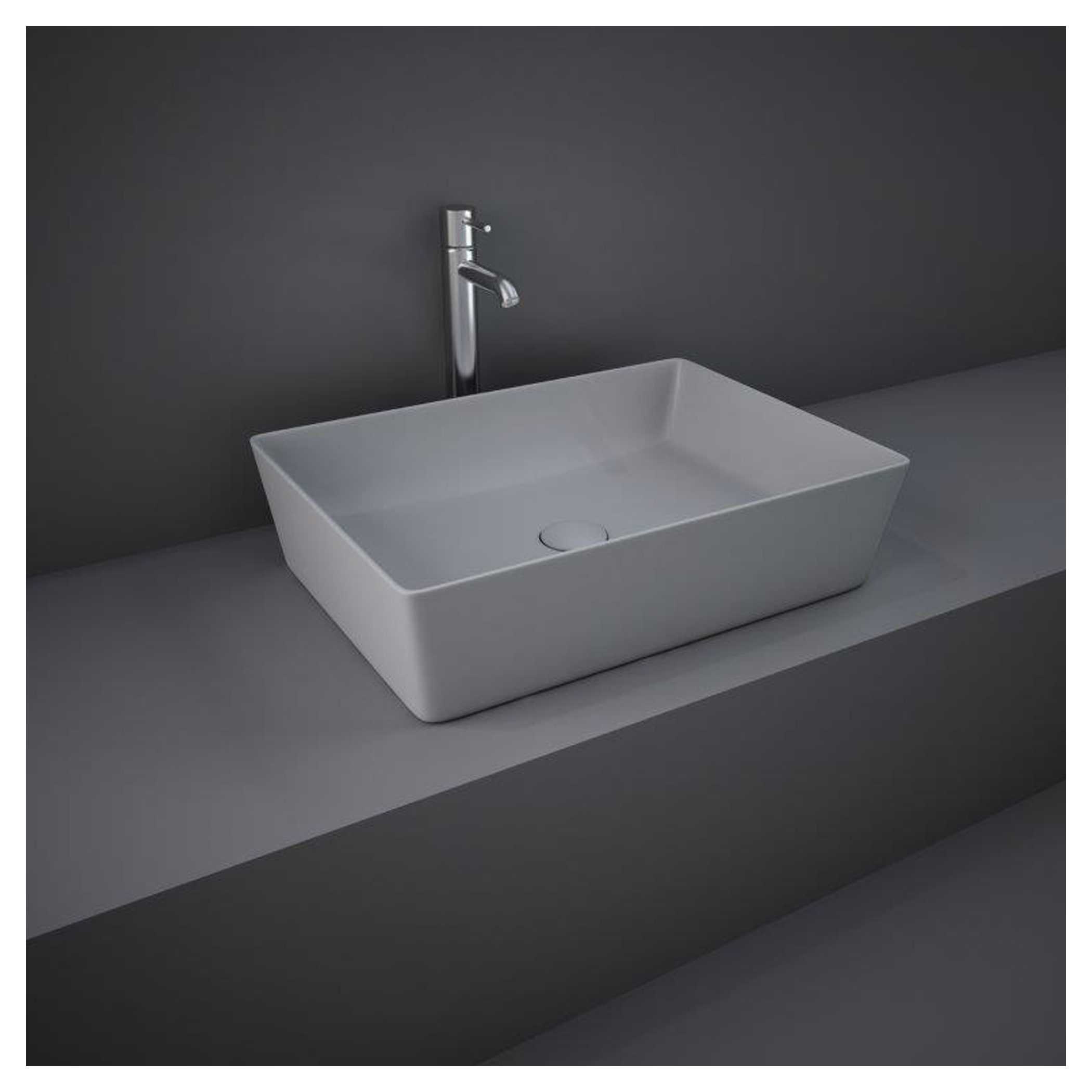 Sleek modern rectangular white bathroom sink with a chrome faucet, minimalist design, mounted on a grey countertop against a dark wall.