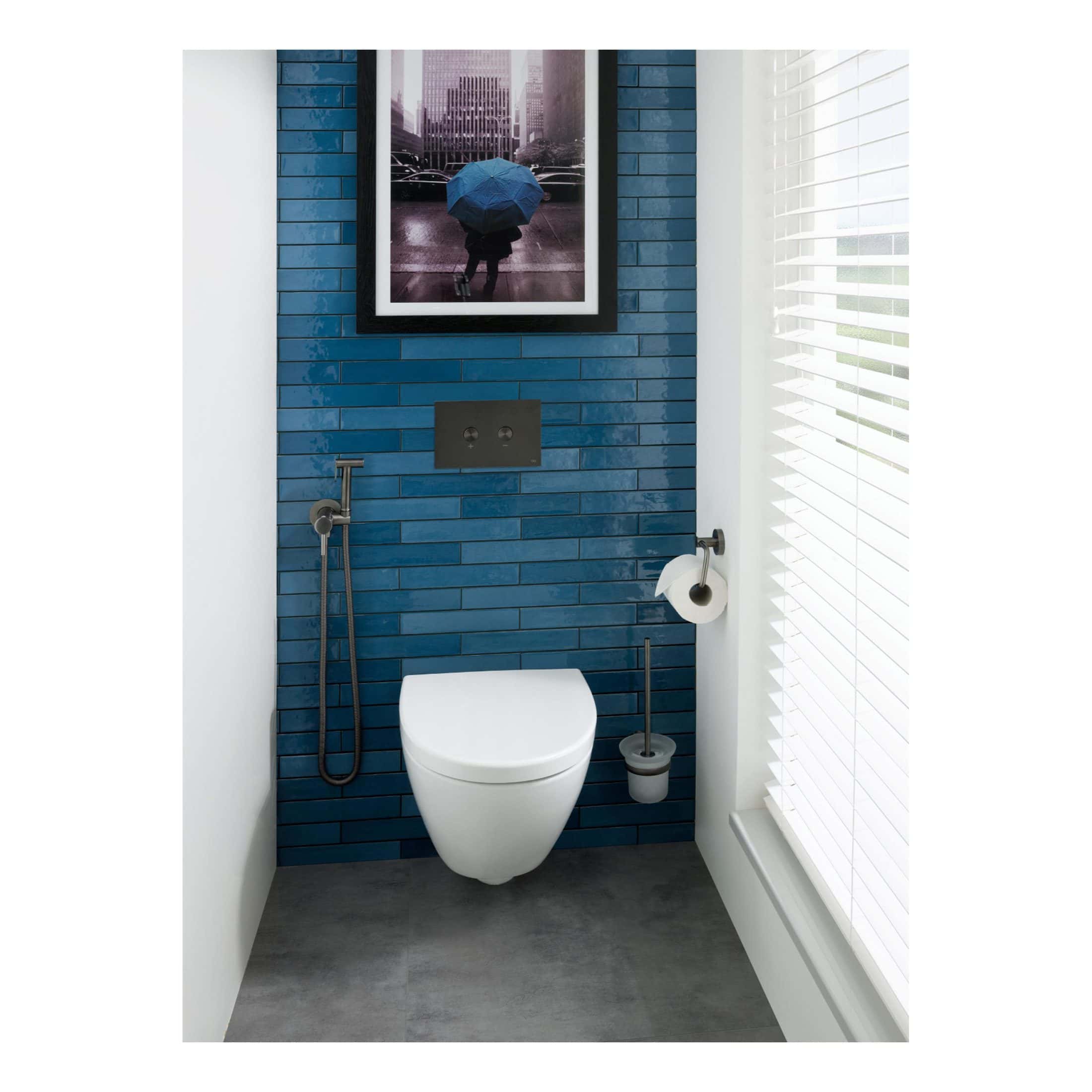 Blue tiled bathroom wall with modern wall-hung toilet, bidet spray, and toilet paper holder, illuminated by natural light through white Venetian blinds, showcasing contemporary bathroom design.