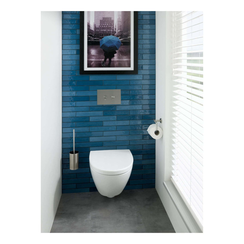 Modern blue brick wall bathroom with wall-mounted toilet, sleek stainless steel toilet brush holder, and contemporary art framed photo, creating a stylish and functional space.
