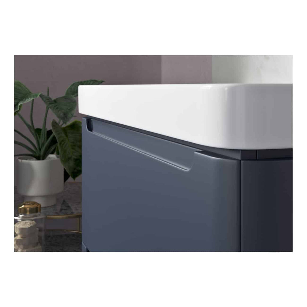 Sleek modern bathroom vanity with white countertop and dark grey cabinetry, featuring a minimalist handle design, set in a contemporary bathroom with decorative plants and accessories.