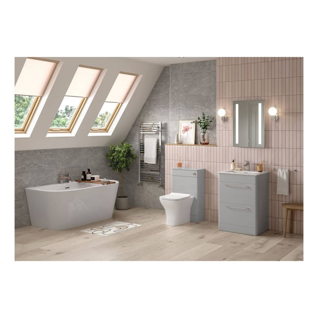Sleek modern bathroom with skylight windows, featuring a white freestanding bathtub, a smart toilet, grey and pink tiled walls, and contemporary vanity units, creating a stylish and functional space.