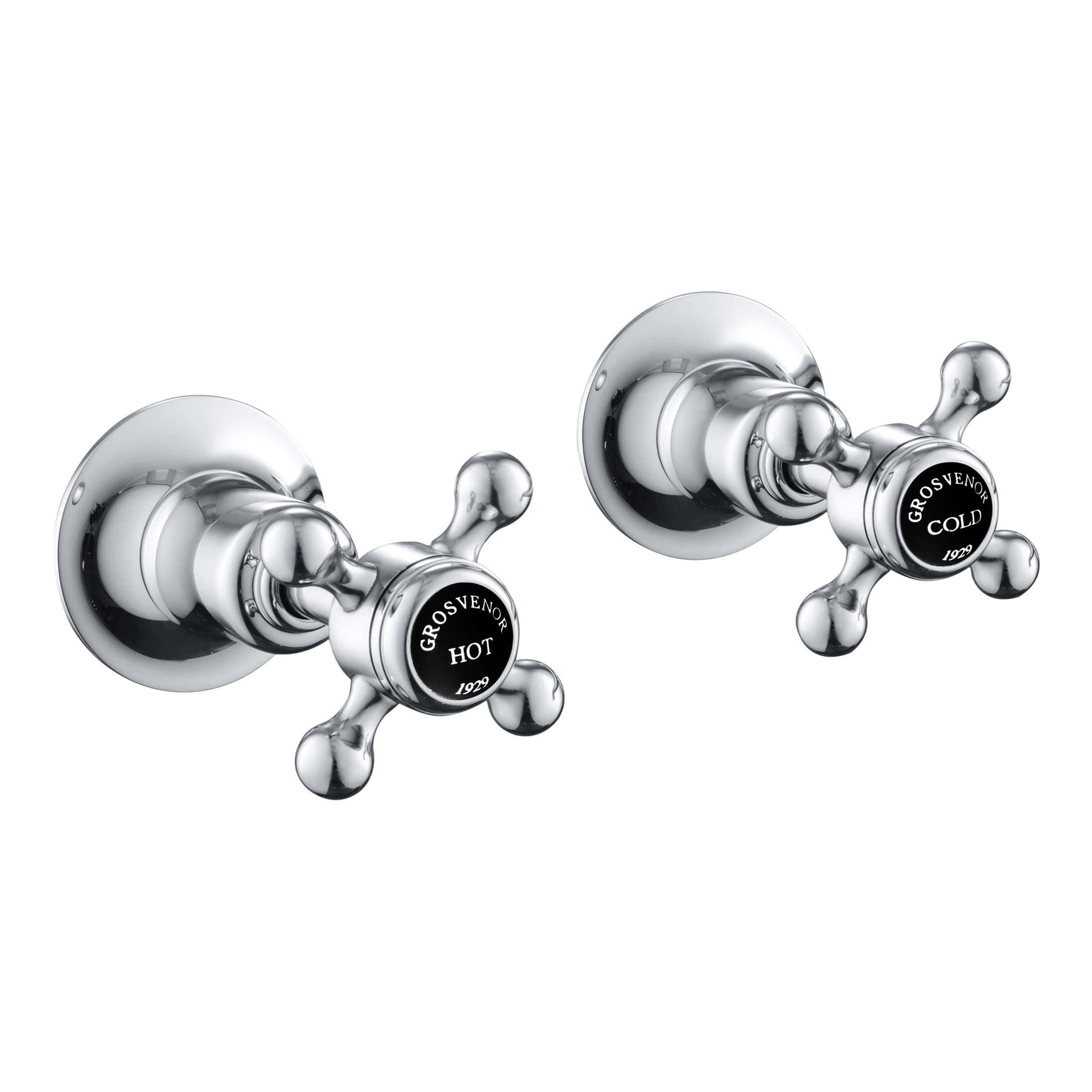 Shiny chrome wall-mounted hot and cold water tap handles with black labels, vintage style bathroom fixture for luxury bath or shower installation.