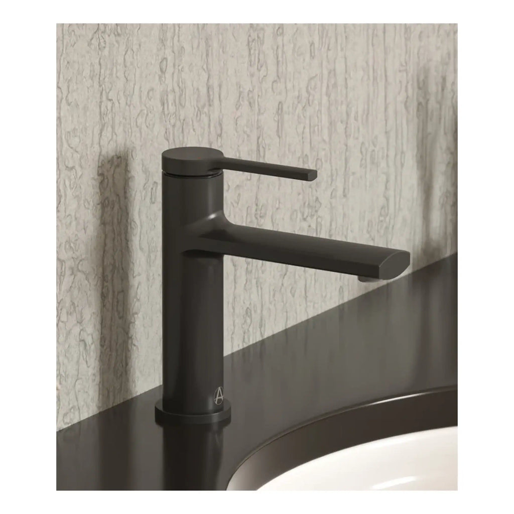 Sleek black bathroom tap mounted on black countertop with textured light grey wall in the background. Ideal for modern bathrooms, showcasing stylish fixtures and contemporary design.