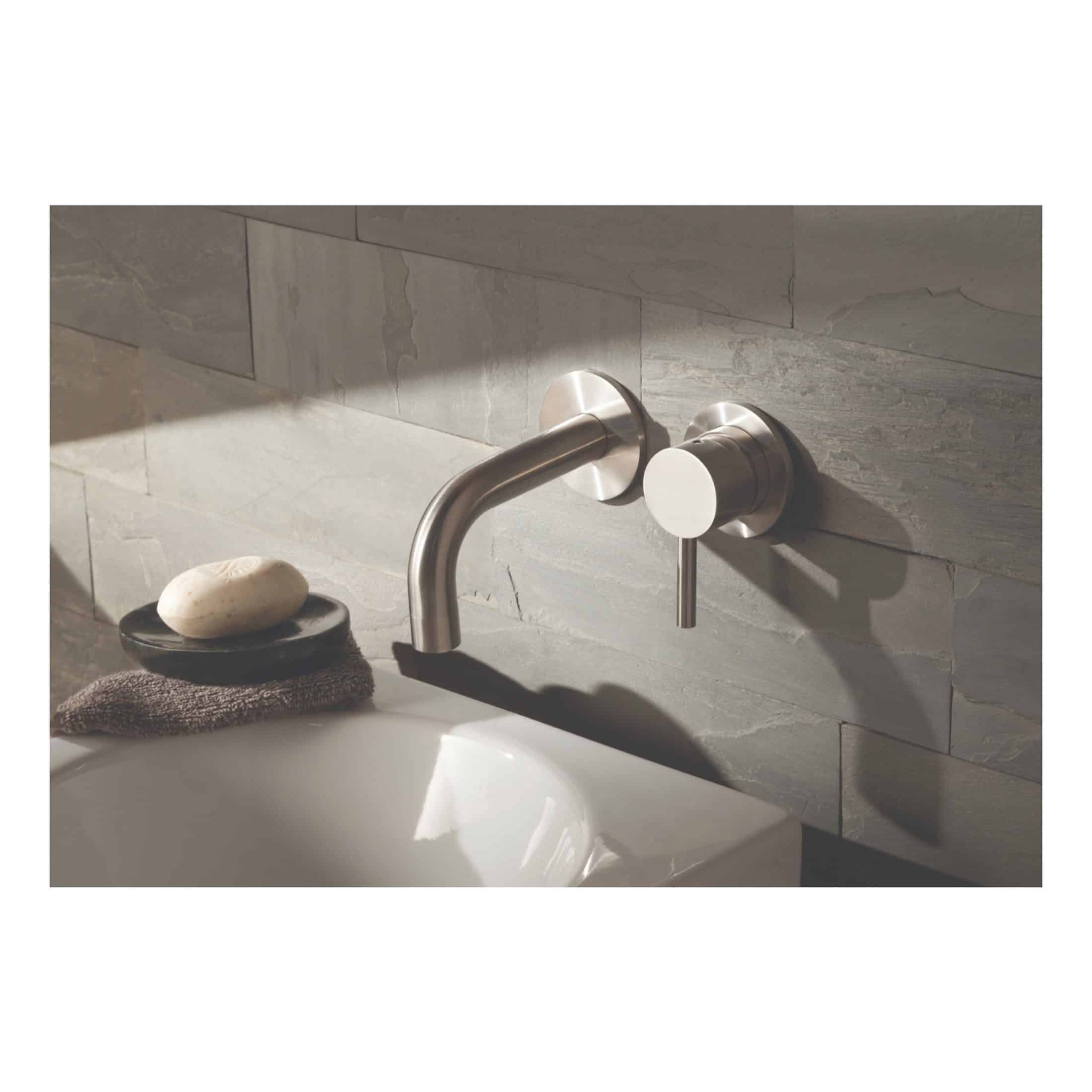 Sleek modern stainless steel bathroom tap with wall-mounted design, set against a grey tiled wall, ideal for contemporary bubly bathrooms and stylish washbasin setups.