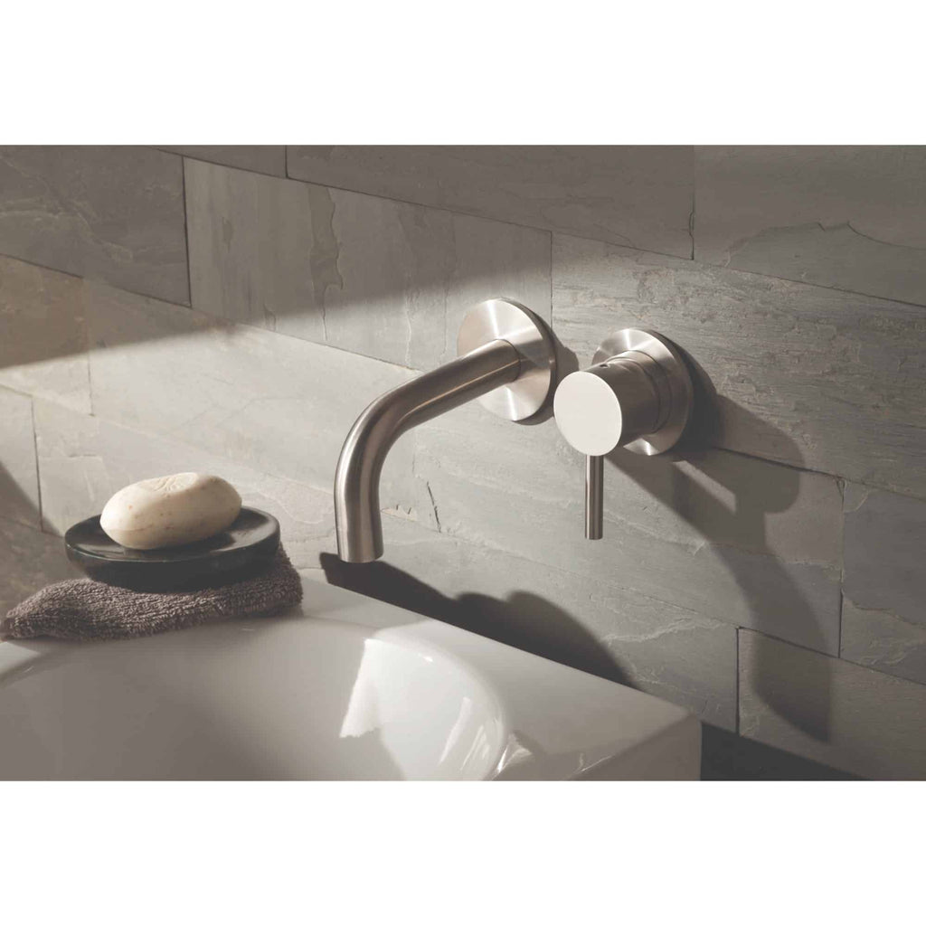 Sleek stainless steel bathroom basin tap with modern wall-mounted design on grey tiled wall, featuring a minimalist style for contemporary bathroom decor.