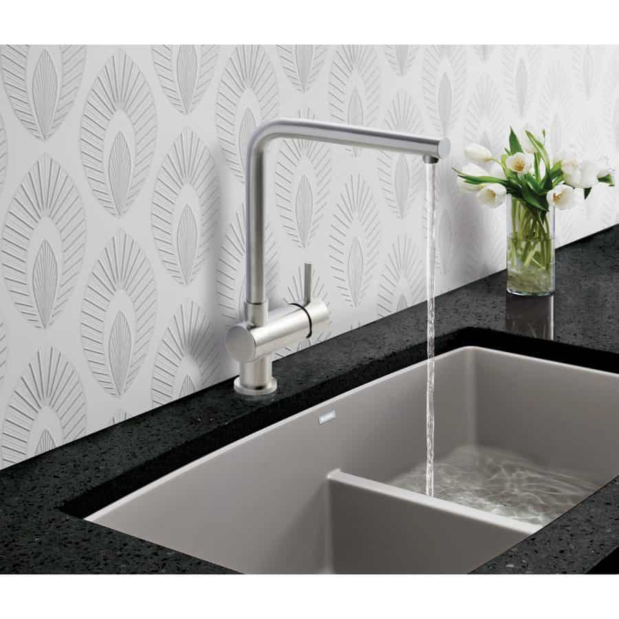Sleek kitchen sink with modern chrome tap and black granite countertop, complemented by a vase of white flowers, showcasing stylish and functional bathroom design.