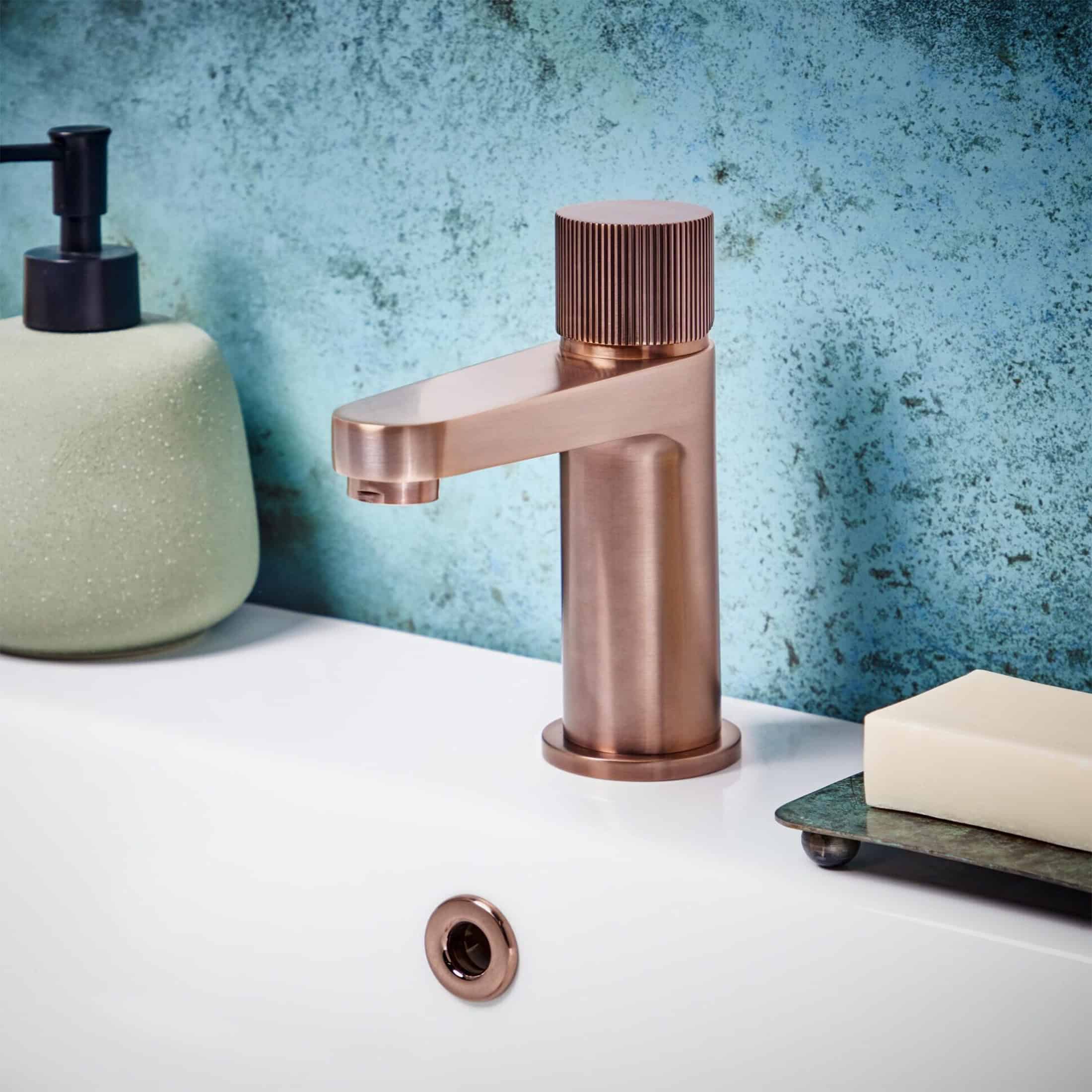 Modern rose gold bathroom tap with a sleek design and textured control knob, complementing contemporary bathroom decor.