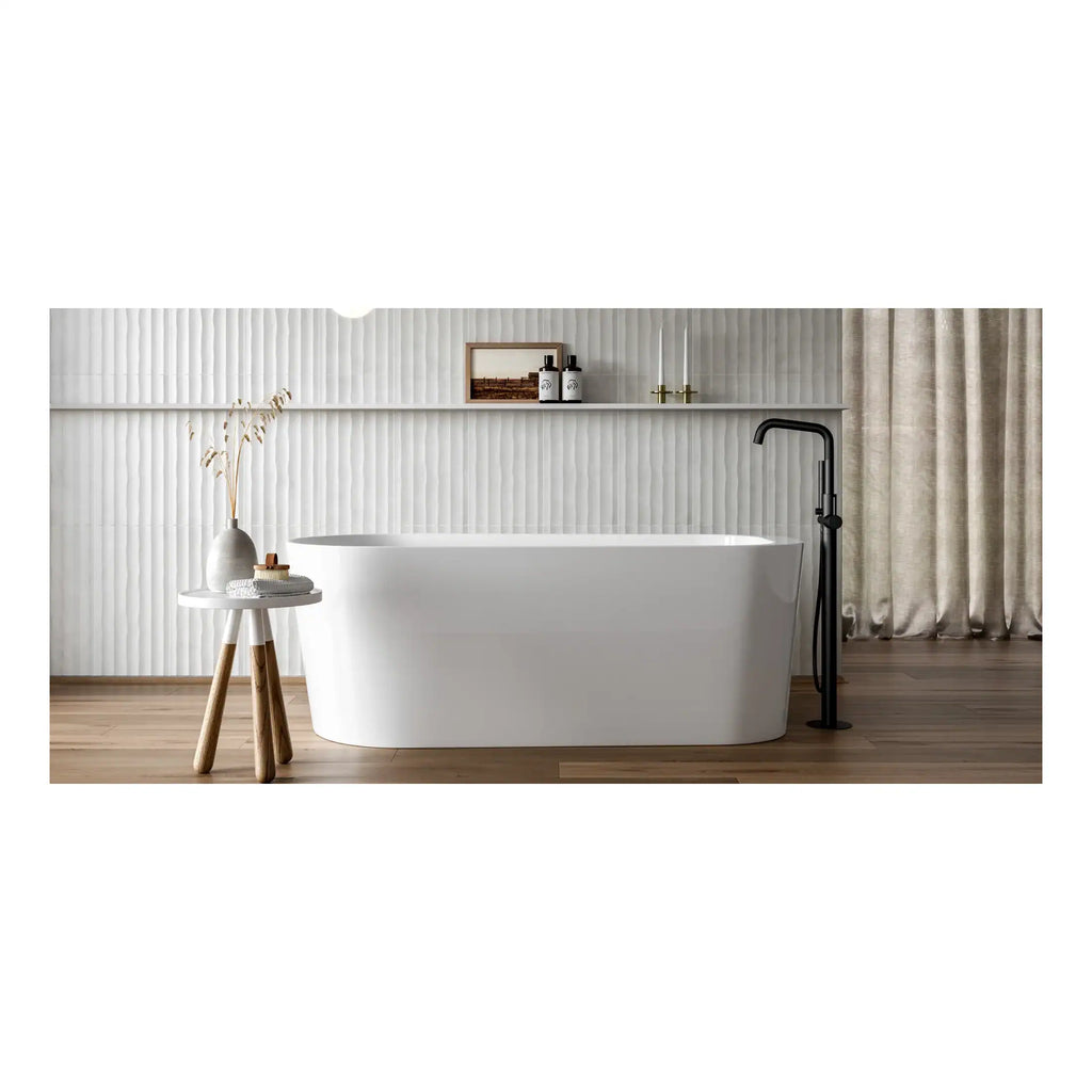 A sleek modern freestanding white bathtub with black floor-mounted tap in contemporary bathroom setting with neutral tones.