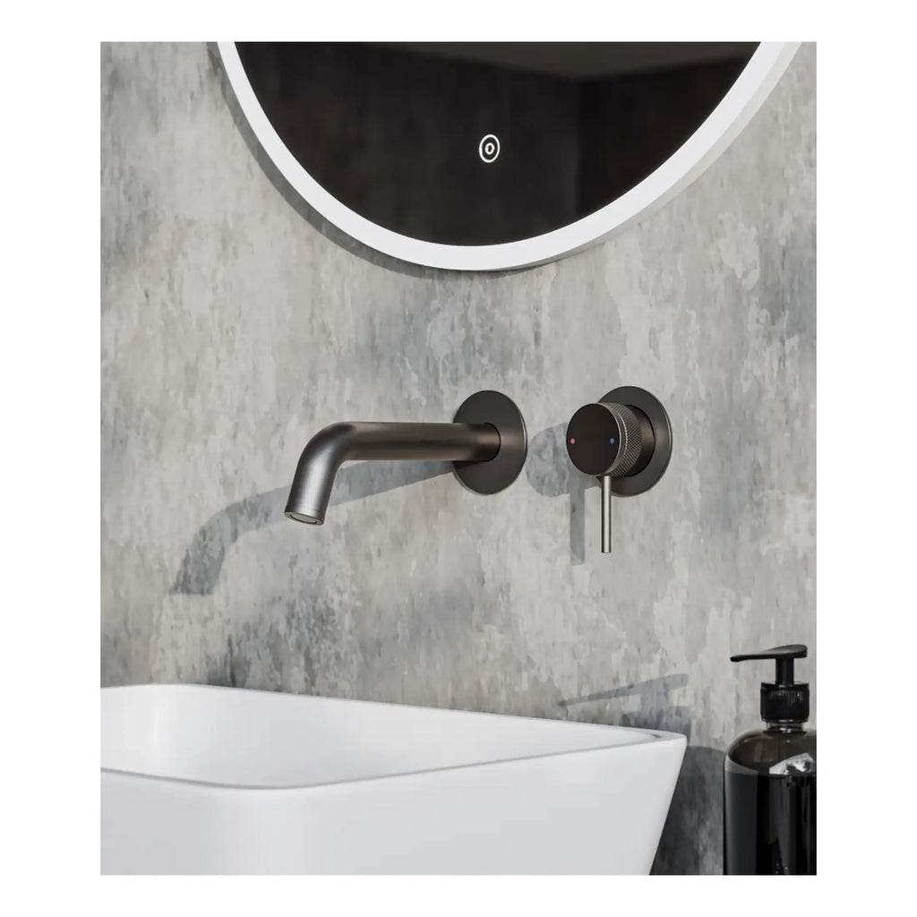Sleek black wall-mounted mixer tap with single handle for modern bathroom sink, set against textured grey wall, complemented by round mirror and black soap dispenser. Perfect for contemporary bathroom design.