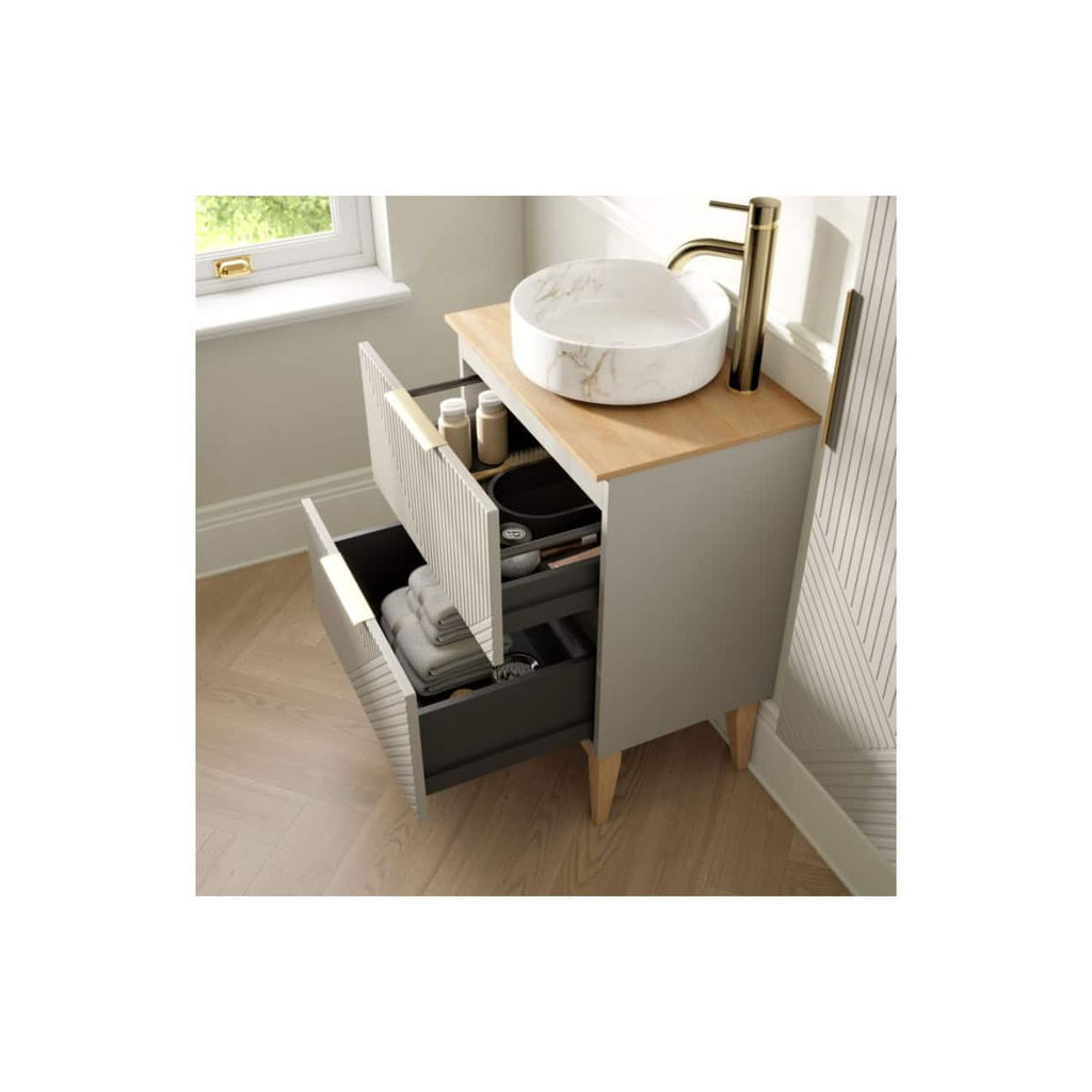 Modern bathroom vanity with wooden countertop, marble vessel sink, brass faucet, and open storage drawers for towels and toiletries, in a bright, minimalist bathroom setting.