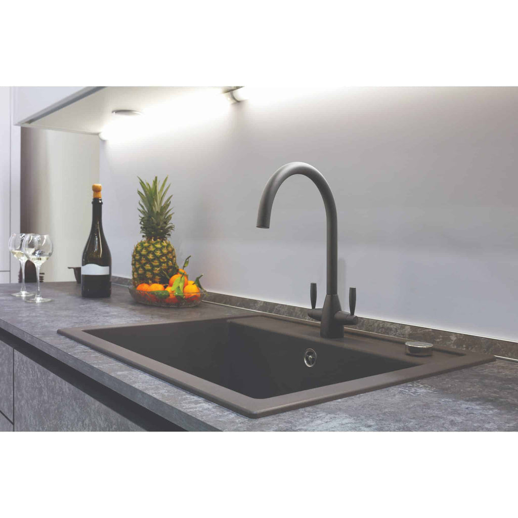 Sleek black kitchen sink with matte black tap in modern kitchen setting, featuring fresh fruit and wine bottles for a stylish, functional look.
