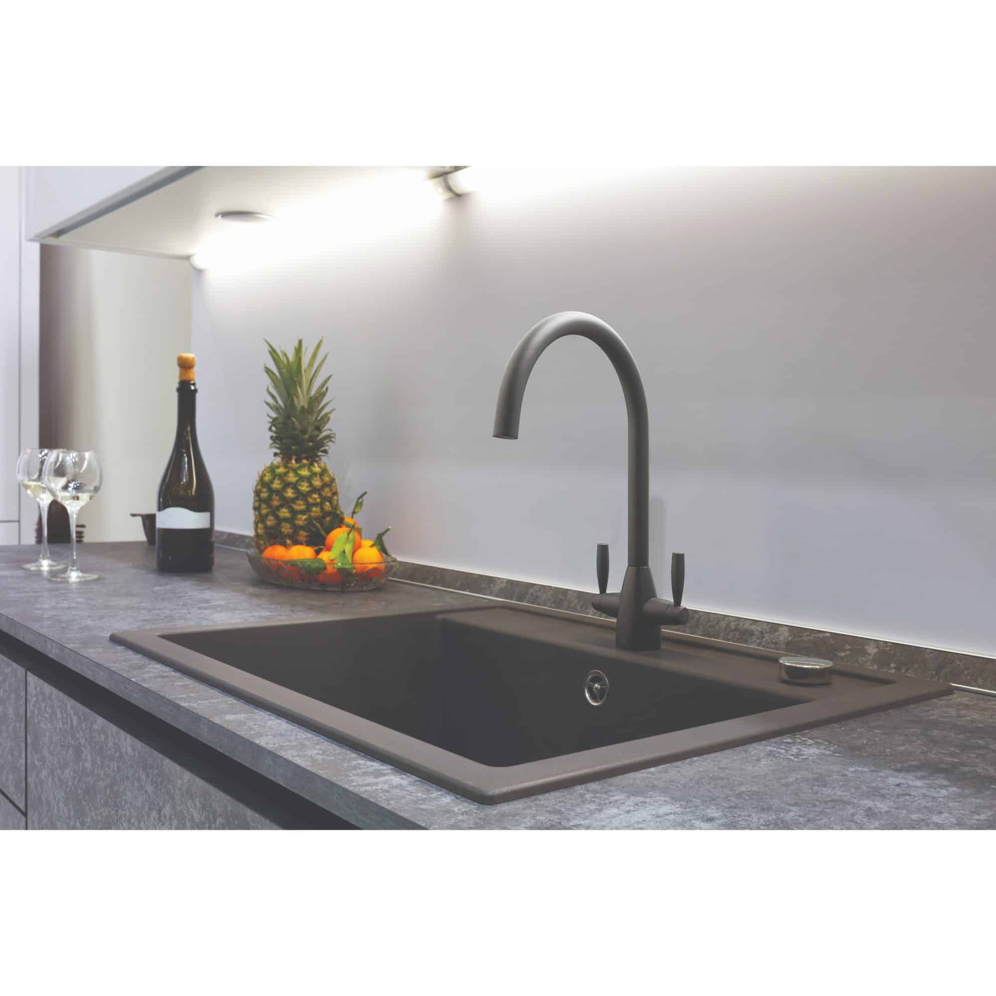 Sleek black kitchen sink with matte black tap in modern kitchen setting, featuring fresh fruit and wine bottles for a stylish, functional look.