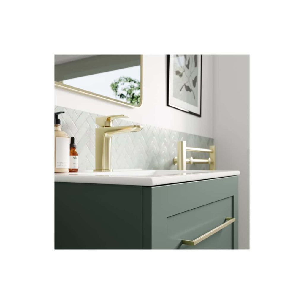 Polished gold bathroom tap and accessories on a green vanity unit with a white basin, modern bathroom decor, and stylish wall tiles, ideal for contemporary bathroom designs and renovations.