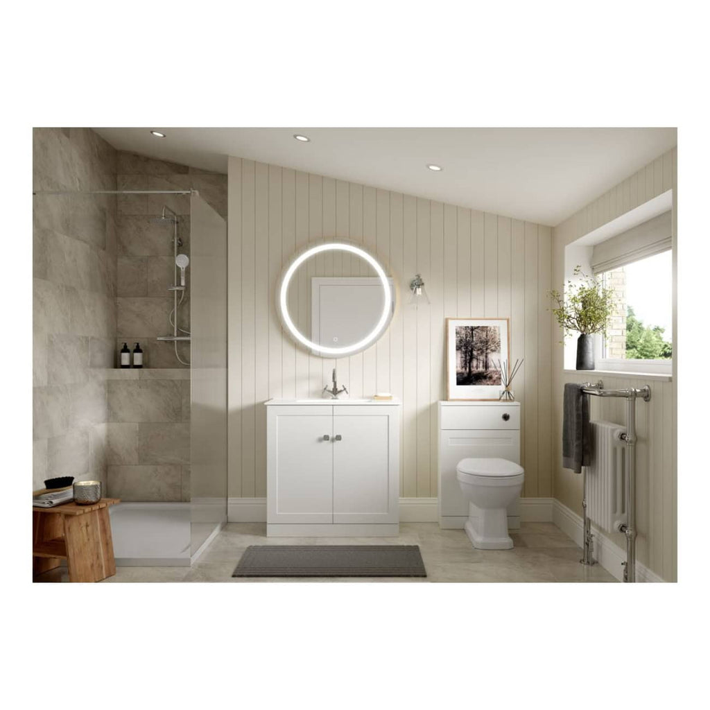 Sleek modern bathroom with shower, white vanity unit, round illuminated mirror, and natural light from window, featuring minimalist design and neutral tones for a relaxing bathroom space.