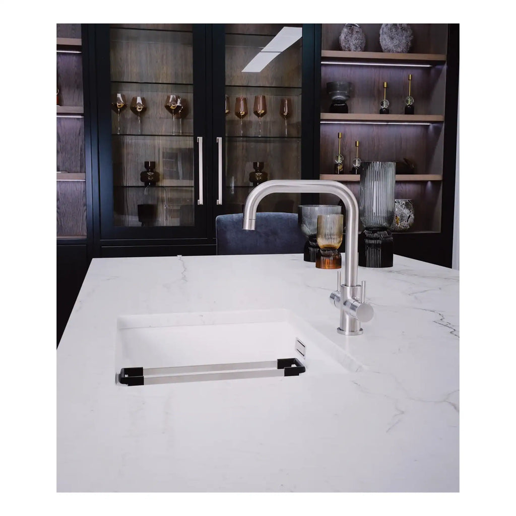 Sleek modern kitchen with a white marble countertop, integrated sink, and contemporary chrome faucet; stylish glass vases and a dark wooden cabinet with glass doors showcasing decorative items, perfect for luxury bathroom or kitchen design.