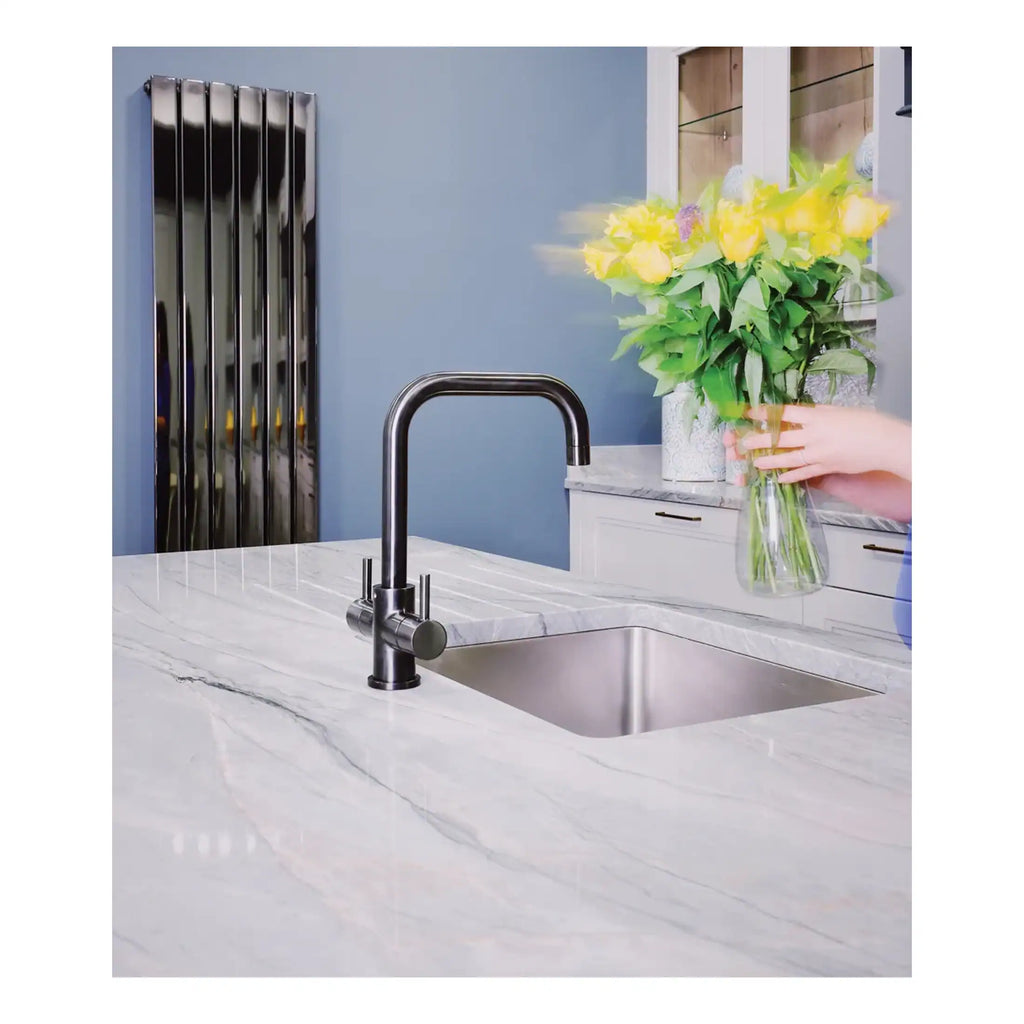 Sleek stainless steel kitchen sink with modern tap, marble countertop, and vibrant yellow flowers in a glass vase in a contemporary bathroom setting.