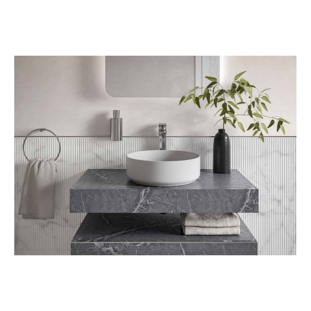 Minimalist bathroom vanity with vessel sink, marble countertop, modern chrome faucet, botanical decor in a black vase, and sleek wall accessories, showcasing elegant bubly.co.uk bathroom design.