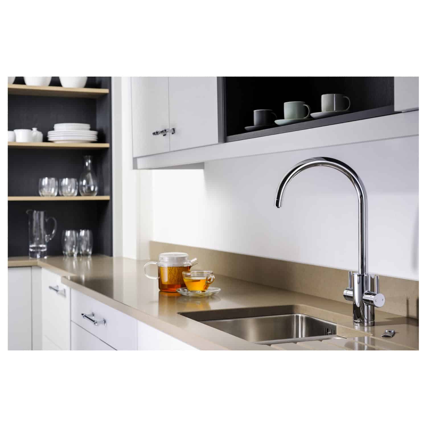 Shiny modern kitchen sink with chrome tap in a sleek, minimalist kitchen featuring white cabinets, open shelving with stylish dishware, and a beige countertop, ideal for contemporary bathroom or kitchen renovations.