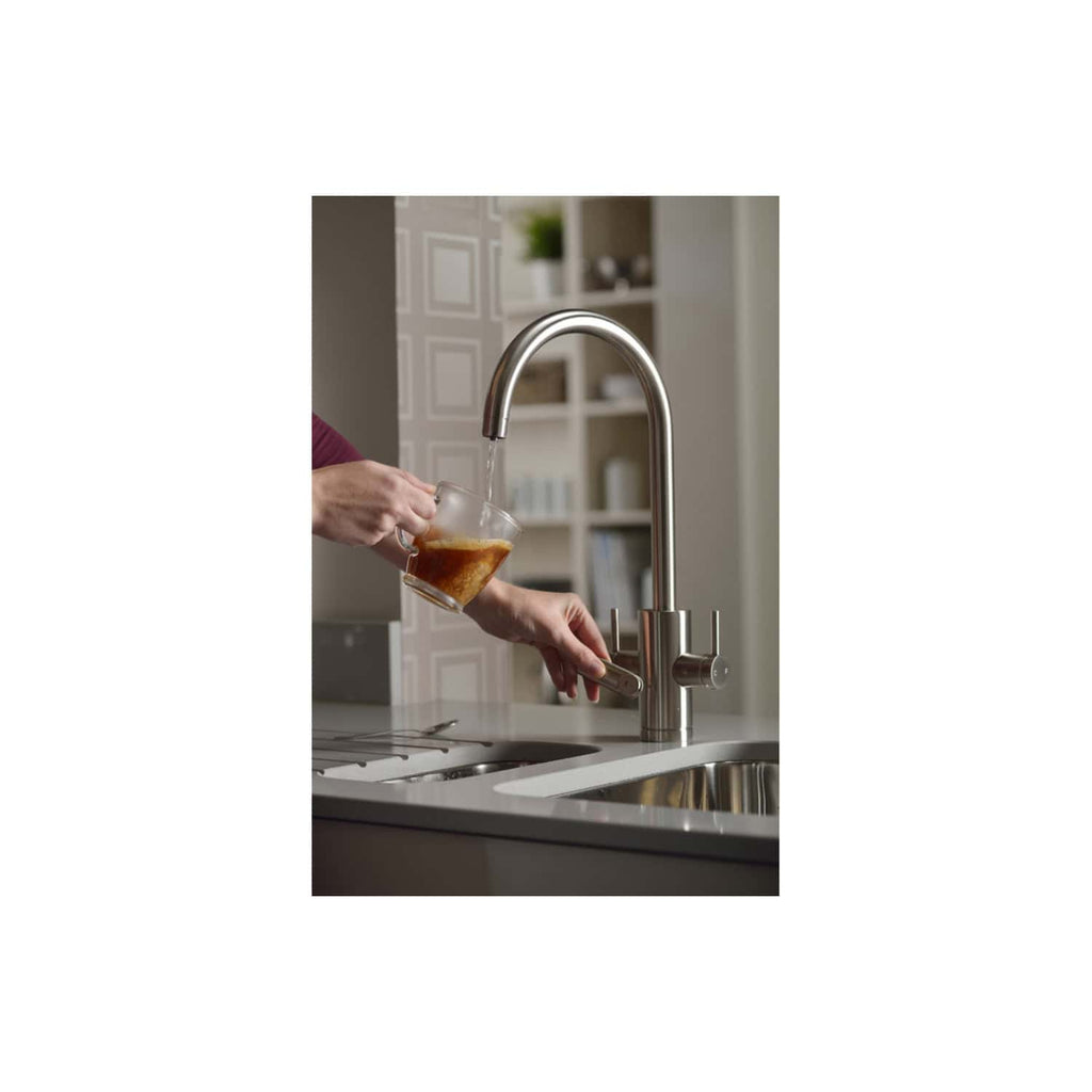 Filling a glass with hot coffee under a modern stainless steel kitchen tap, showcasing contemporary bathroom fixtures and stylish kitchen design.