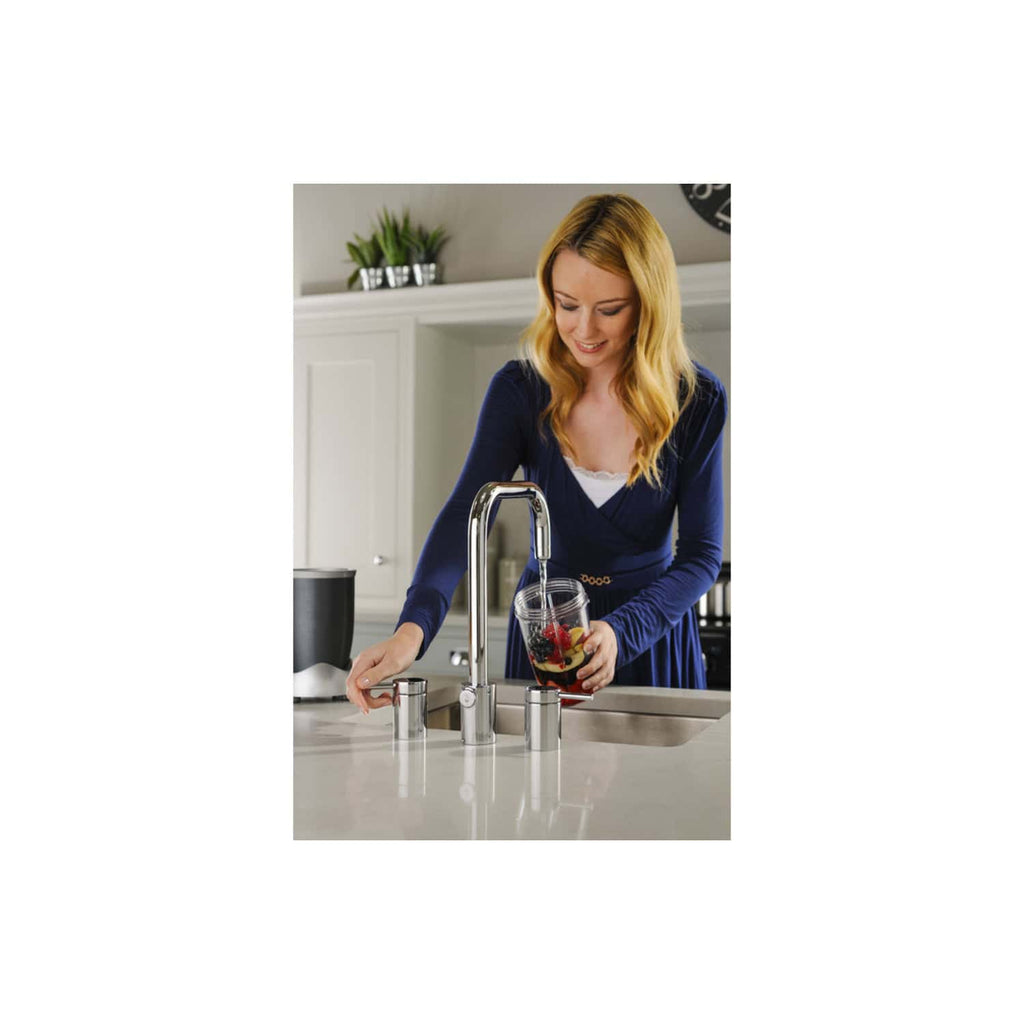Shiny modern kitchen tap with water running, woman filling glass with blackcurrant juice, stylish kitchen with white cabinets and plants, bubble.co.uk bathroom décor.