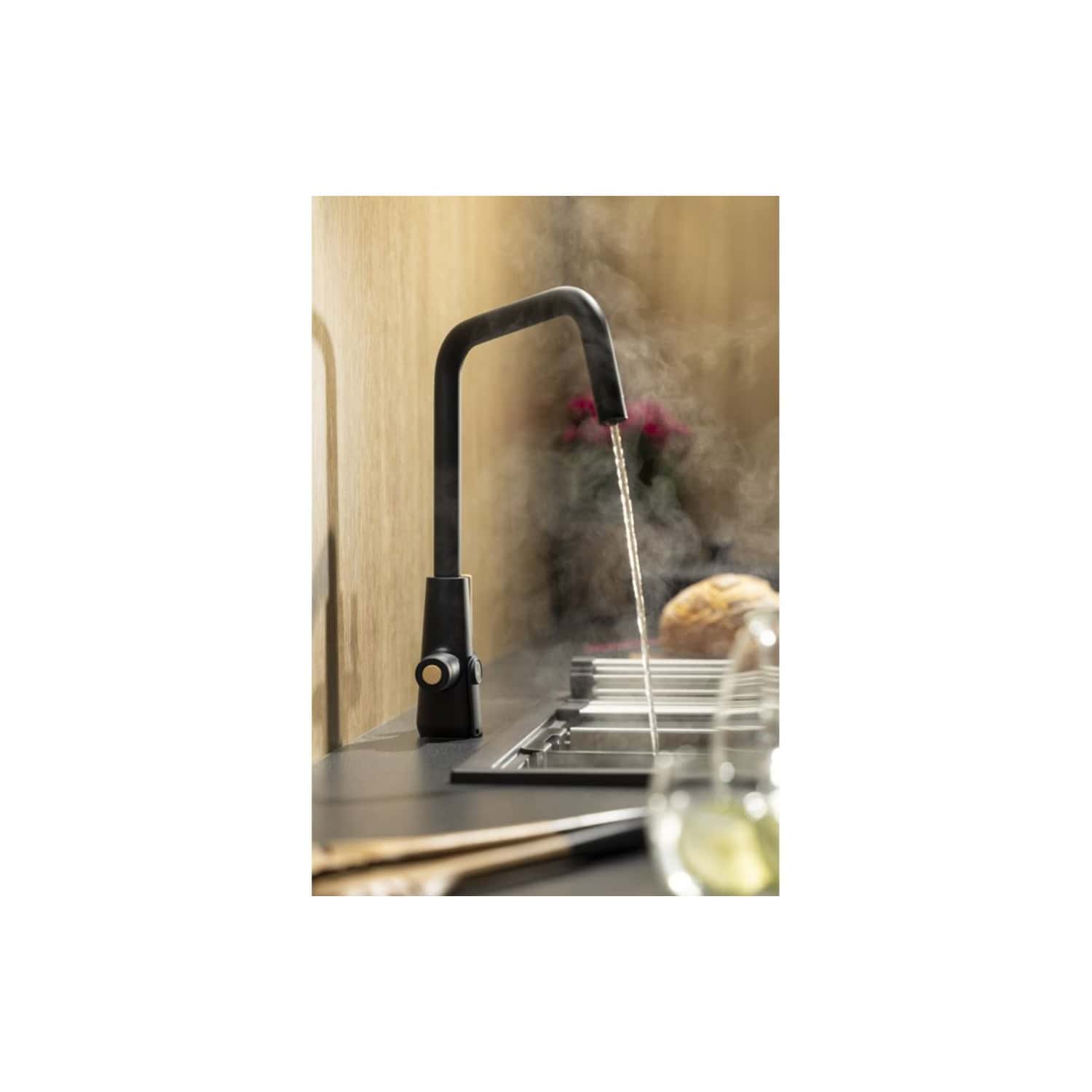 Sleek black kitchen tap with steaming hot water flowing over a modern black sink in a contemporary kitchen setting. Perfect for stylish, functional kitchen renovation with high-quality fixtures.