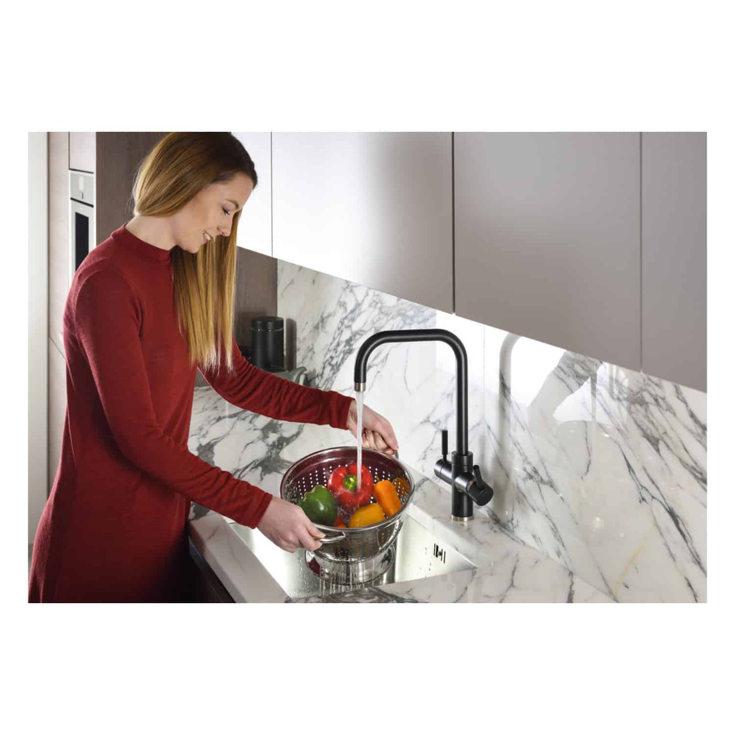 Brushed black kitchen tap with modern kitchen sink and marble countertops in a contemporary bathroom setting.