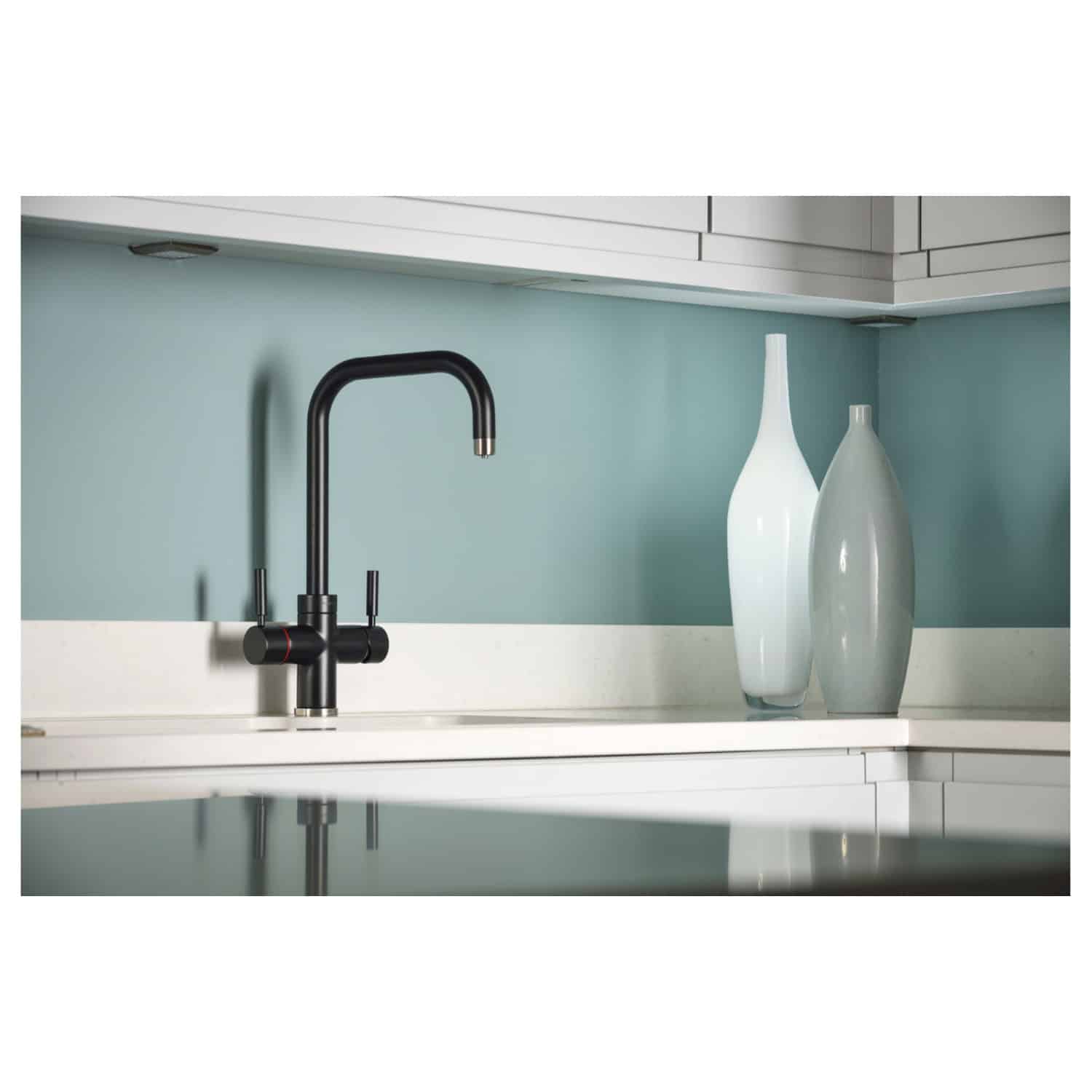 Sleek black kitchen tap with modern design, paired with decorative vases on a white countertop in a contemporary bathroom or kitchen setting.