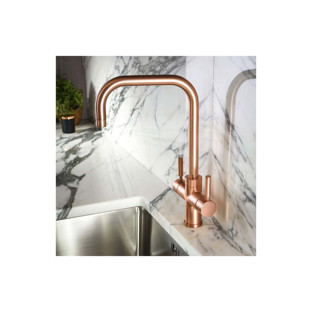 Sleek copper kitchen tap installed over a stainless steel sink with a marble countertop and backsplash, showcasing modern bathroom and kitchen design ideas.