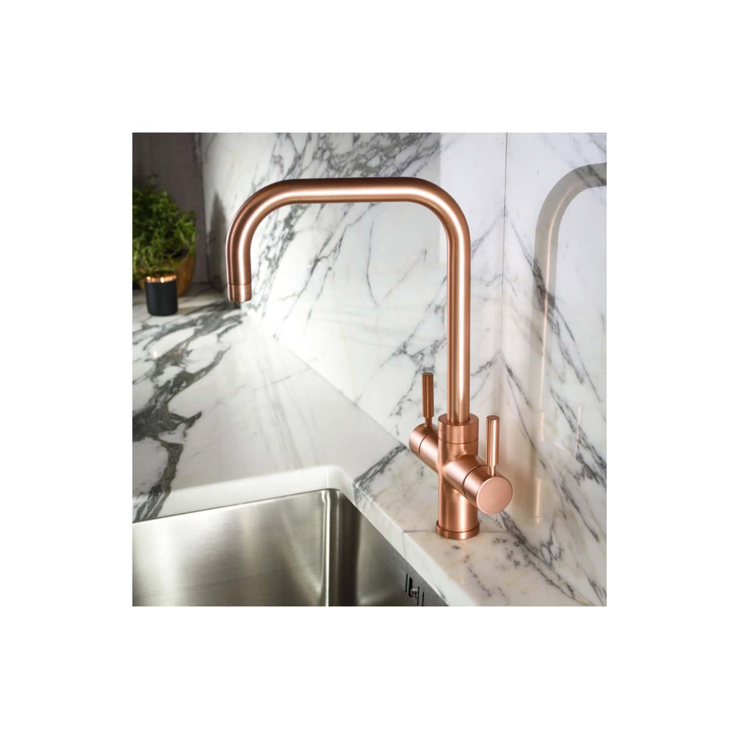 Sleek copper kitchen tap installed over a stainless steel sink with a marble countertop and backsplash, showcasing modern bathroom and kitchen design ideas.
