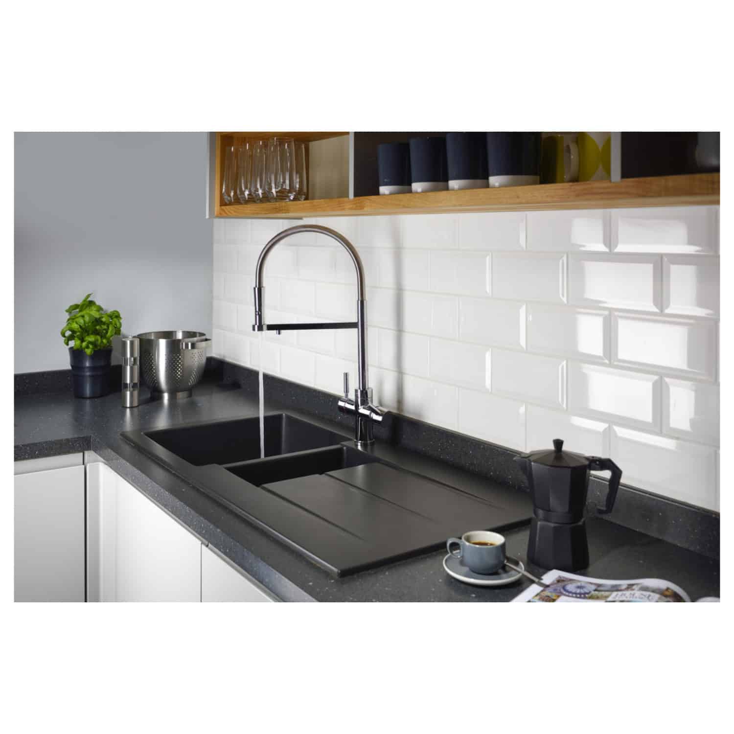Bright modern kitchen sink with black double-basin and sleek chrome faucet, set against white subway tile backsplash, featuring a coffee maker, cup, and fresh basil on black countertop, with open shelving above.