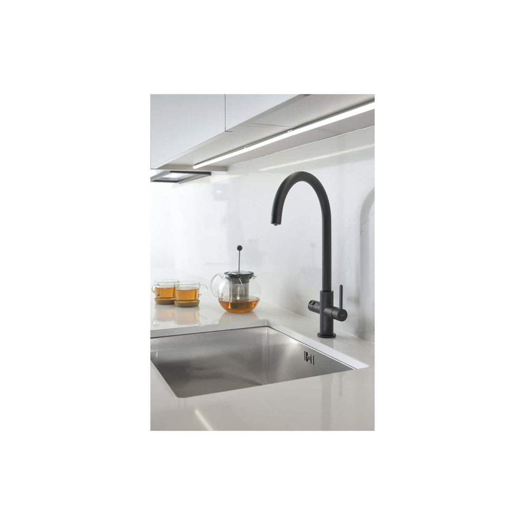 Sleek black kitchen tap with high-arching spout over modern sink, minimalist white countertop with tea infuser and cups. Stylish, contemporary kitchen design from Bubly Bathrooms.