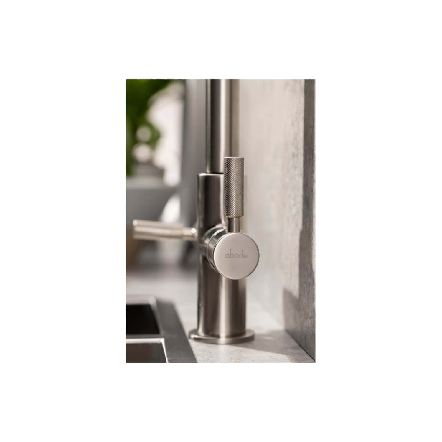 Elevated close-up of stainless steel kitchen faucet with modern design and textured handle, mounted on a concrete wall, ideal for contemporary bathroom or kitchen renovations.