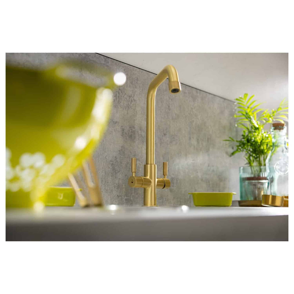 Sleek gold kitchen tap with a modern design, complemented by vibrant green dishware and fresh plants for a stylish and contemporary bathroom or kitchen setting. Perfect for upgrading your space.