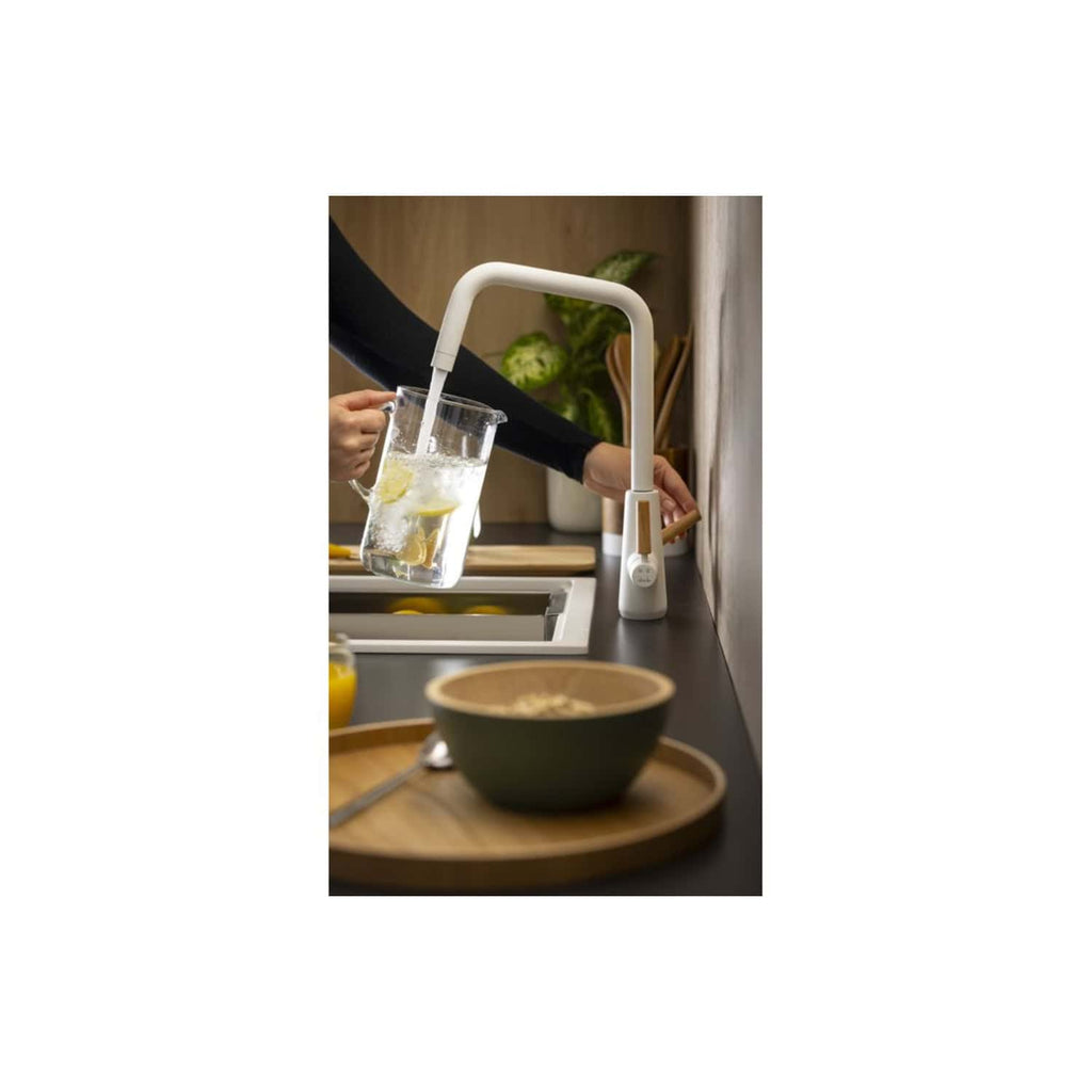 Sleek white kitchen faucet with touchless operation, filling glass with water in modern kitchen setting.