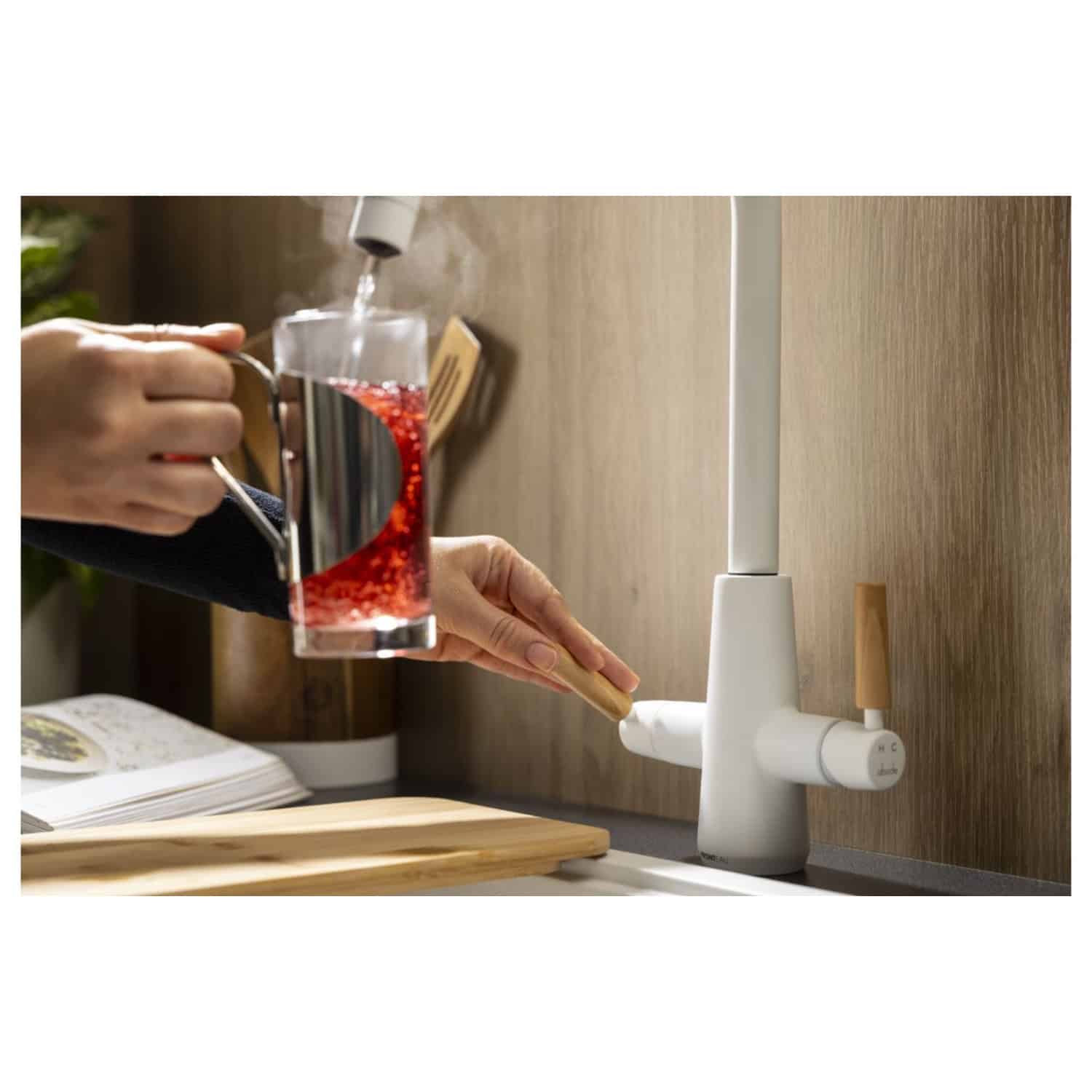 Refreshing kitchen hot and cold water tap with modern white and wooden finish and a person pouring red juice into a glass for healthy lifestyle.