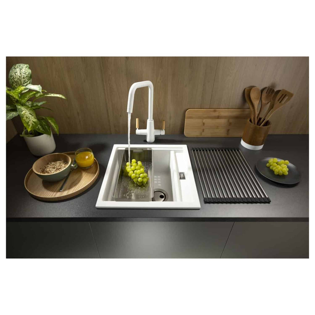 Sleek white kitchen sink with modern fixtures featuring a pull-out spray tap, surrounded by fresh grapes, wooden utensils, and a potted plant, creating a stylish kitchen setup.