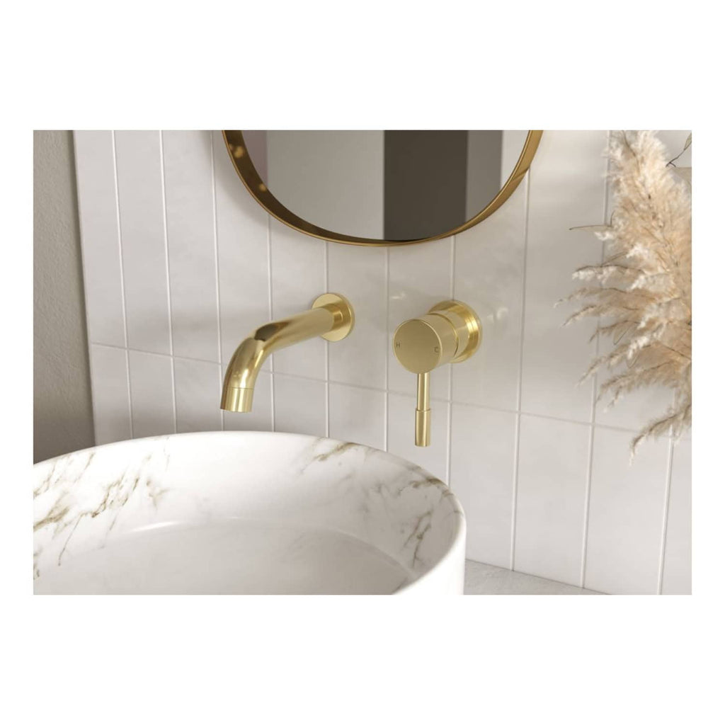 Sleek gold wall-mounted bathroom sink tap with modern design, paired with a marble bowl sink and a round mirror, creating a luxurious and stylish bathroom setting.