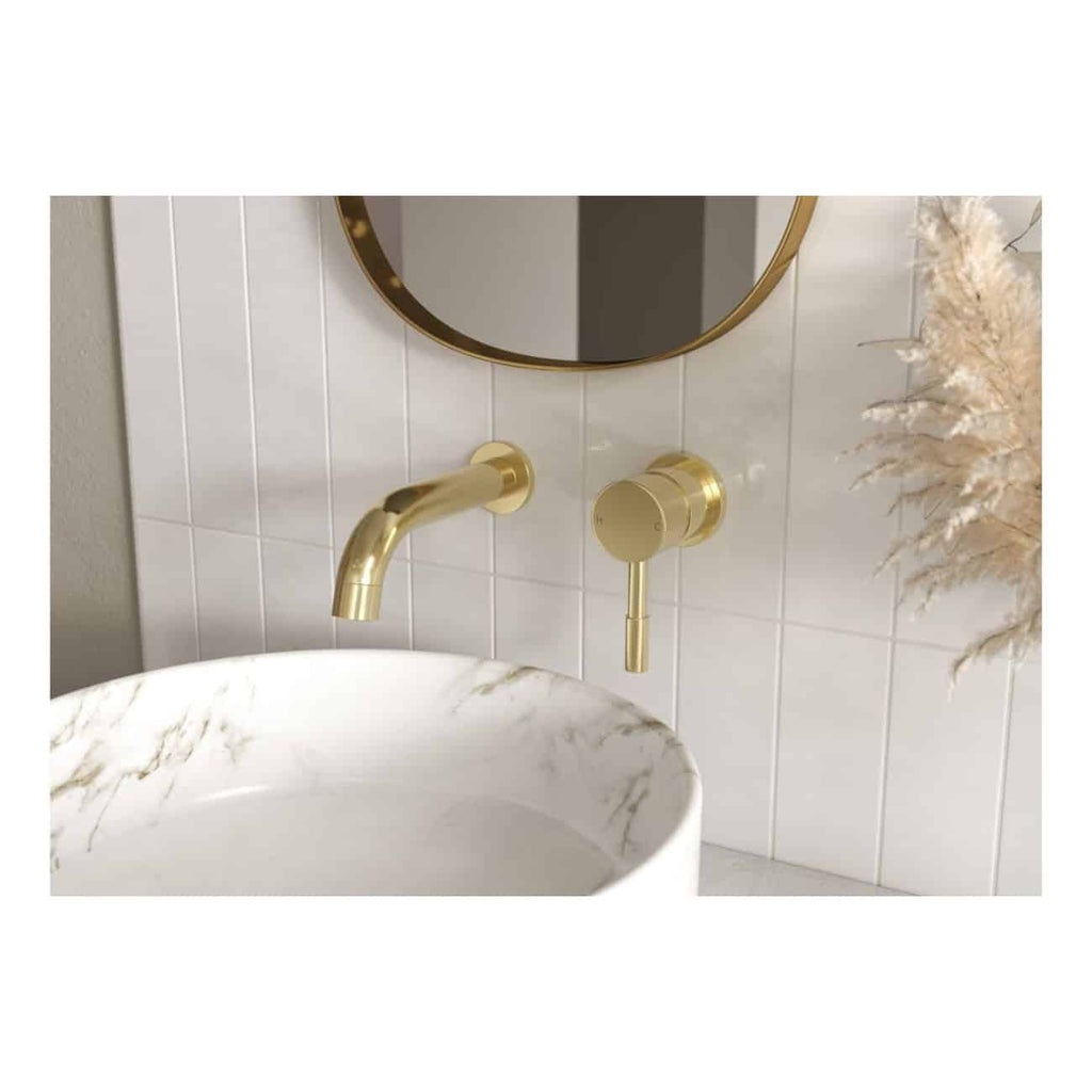 Sleek gold bathroom tap and control handle above a modern marble vessel sink with white tiled wall and round mirror, showcasing luxury bathroom fixtures by Bubly Bathrooms.