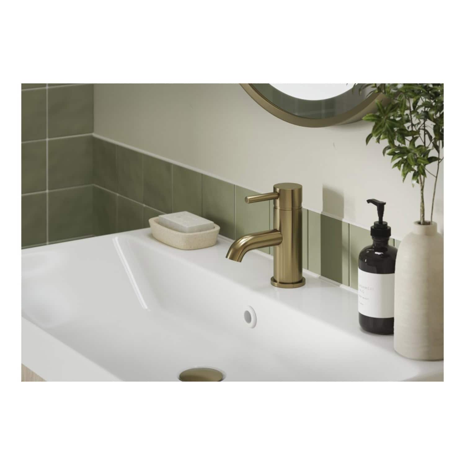 Sleek bathroom sink with modern brushed gold faucet, soap dispenser, and minimalist decor, featuring green tiled walls and a stylish round mirror. High-quality bathroom fixtures by Bubly Bathrooms.