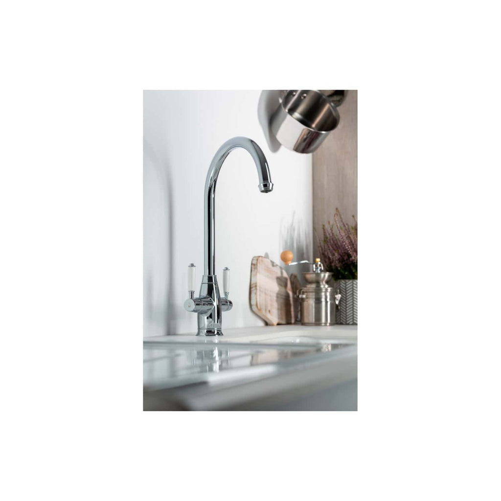 Shiny chrome kitchen sink faucet with a high arc spout, mounted on a white countertop in a modern kitchen setting.