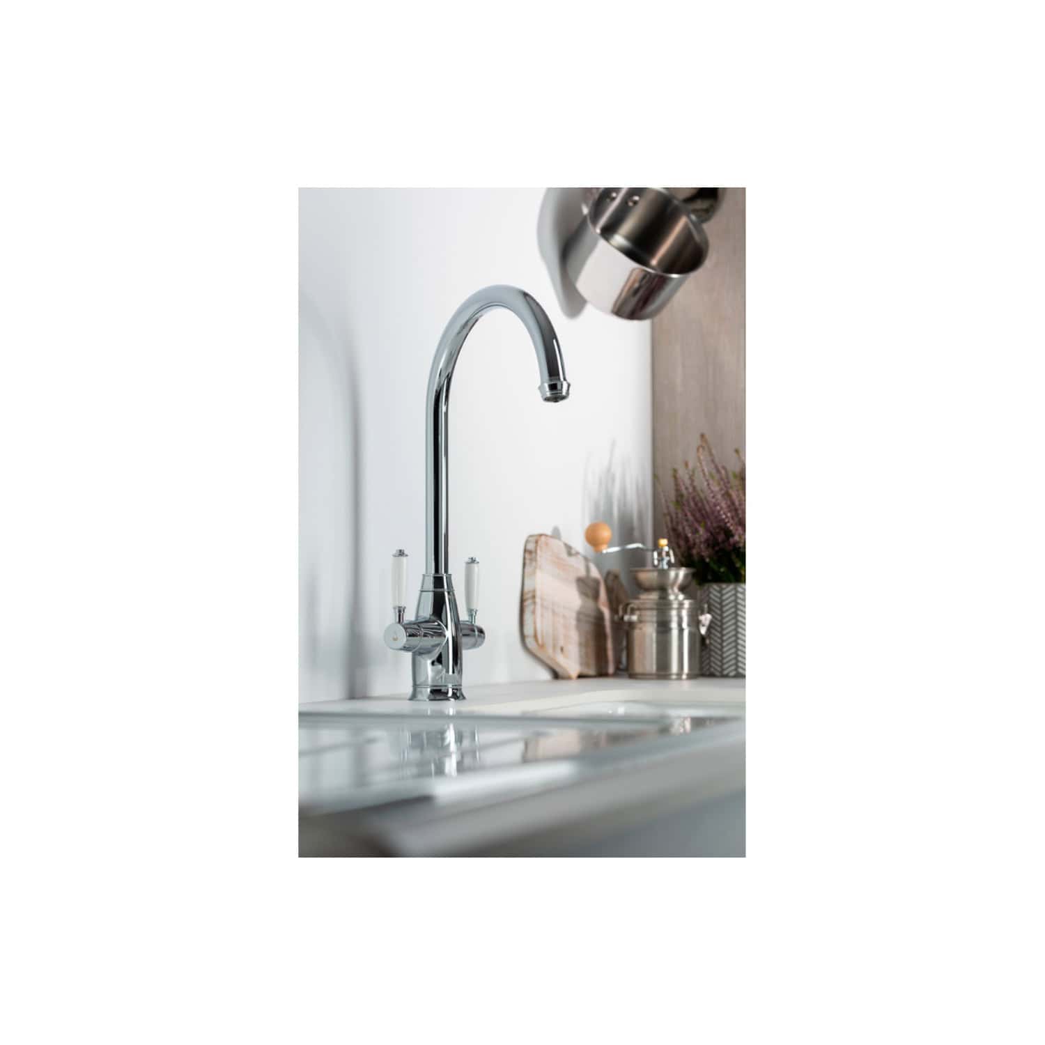 Shiny chrome kitchen sink faucet with a high arc spout, mounted on a white countertop in a modern kitchen setting.