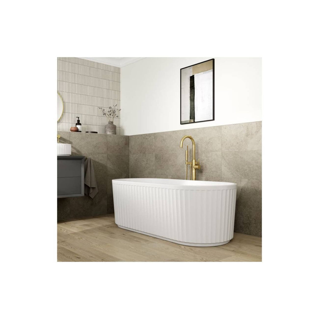 Sleek modern freestanding white bathtub with vertical ribbed design and gold-finished fixtures in a contemporary bathroom setting.