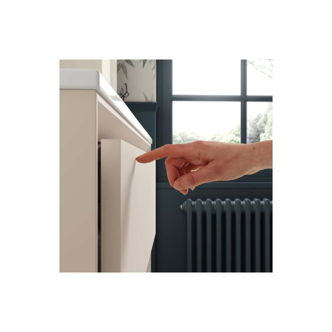 Button to open or close a cabinet door in a modern bathroom with a dark radiator and large window, showcasing high-quality bathroom furniture and smart storage solutions from Bubly Bathrooms.