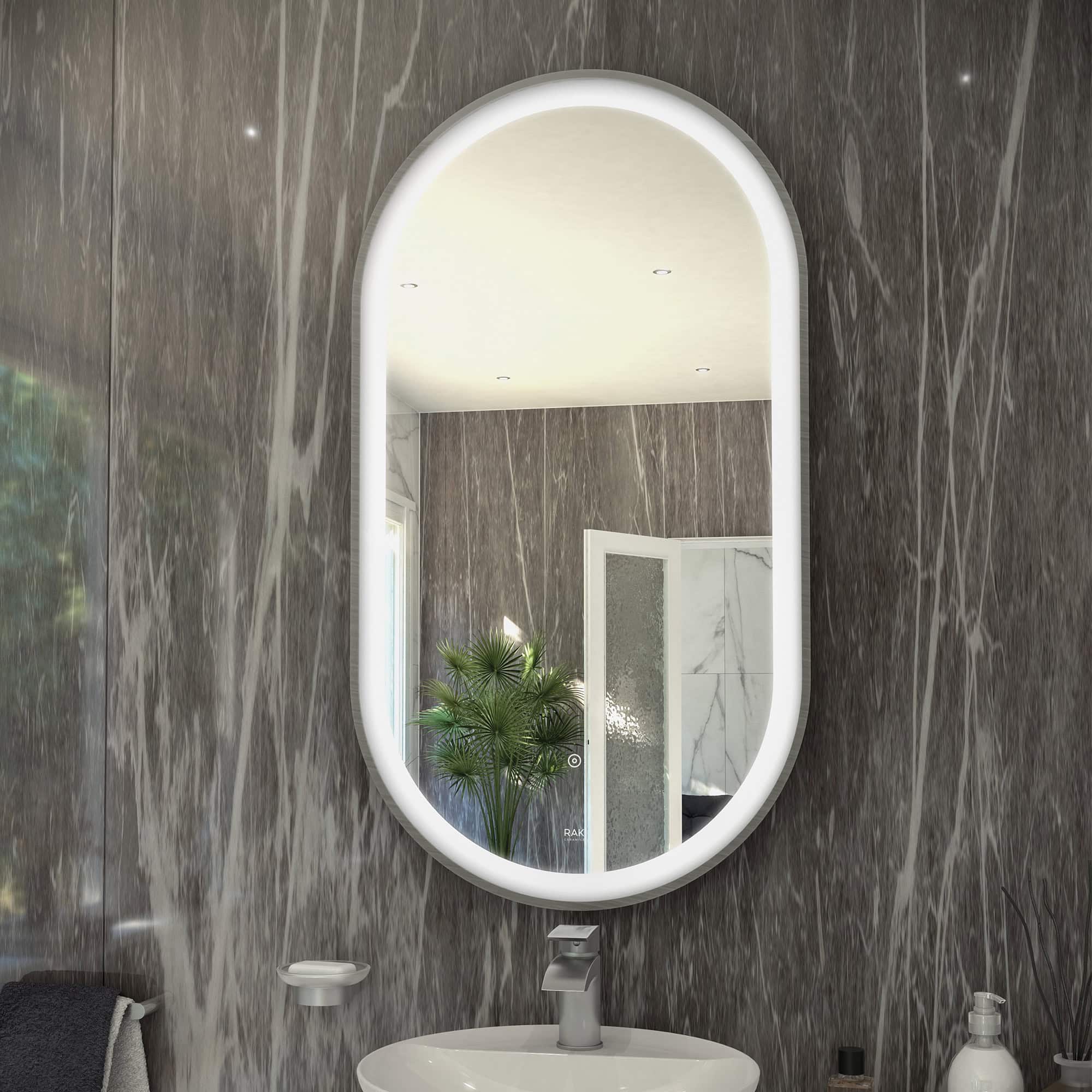 Modern oval bathroom mirror with LED lighting mounted on a marble-effect wall in a contemporary bathroom.