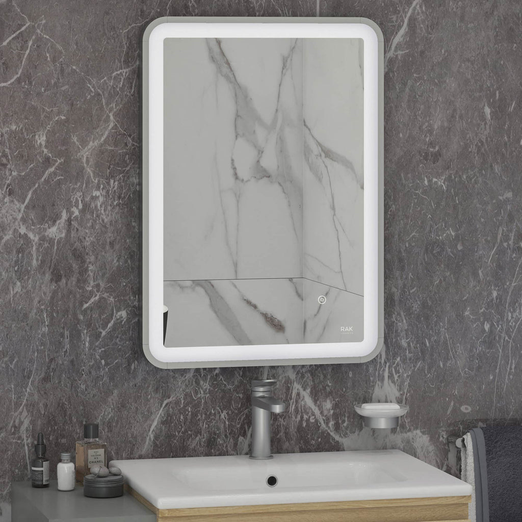 Sleek modern bathroom mirror with integrated LED lighting above a marble-effect bathroom vanity with personalised toiletries and accessories.