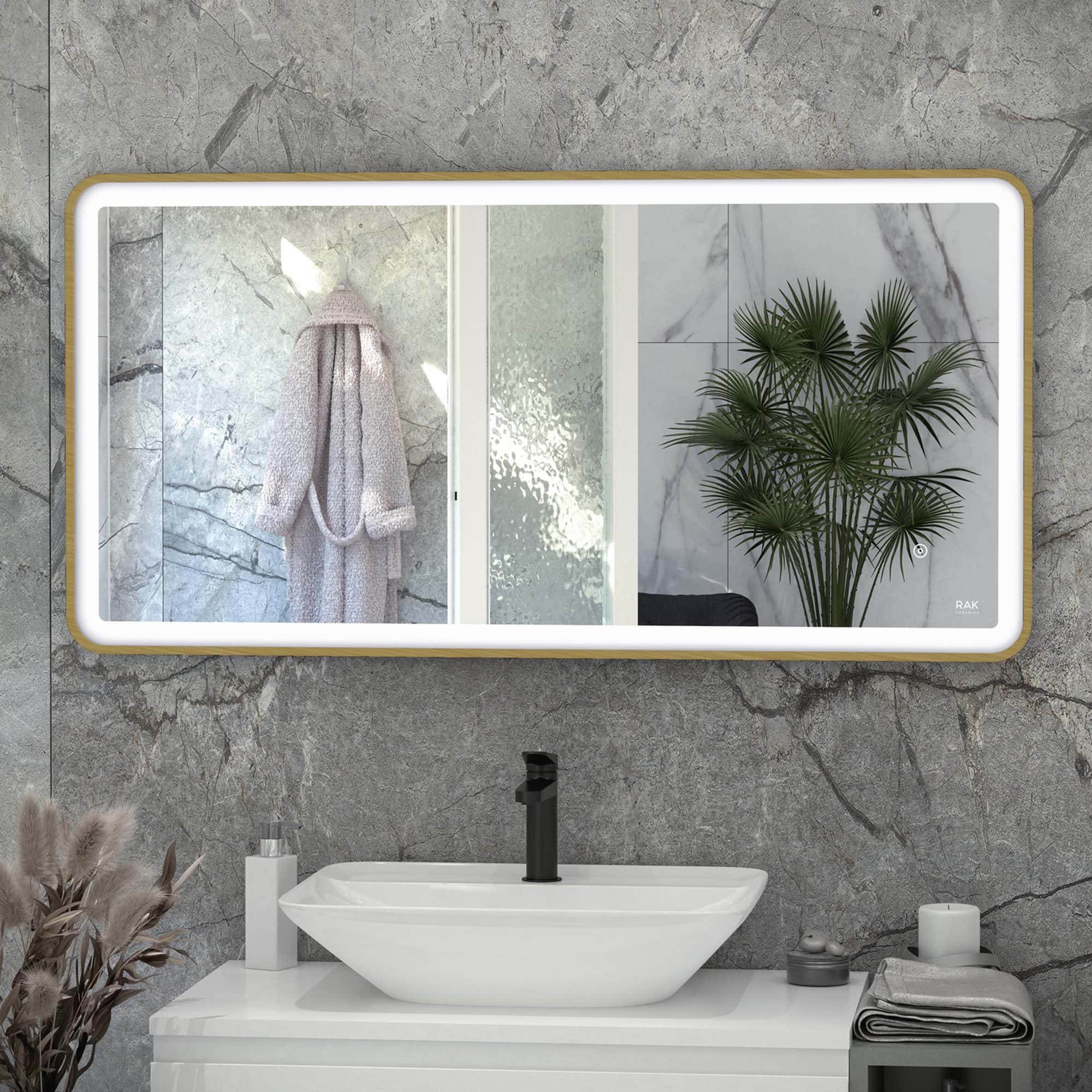 Modern bathroom with stylish mirror, black faucet, and marble wall behind a white basin with decorative towels, plant, and accessories.