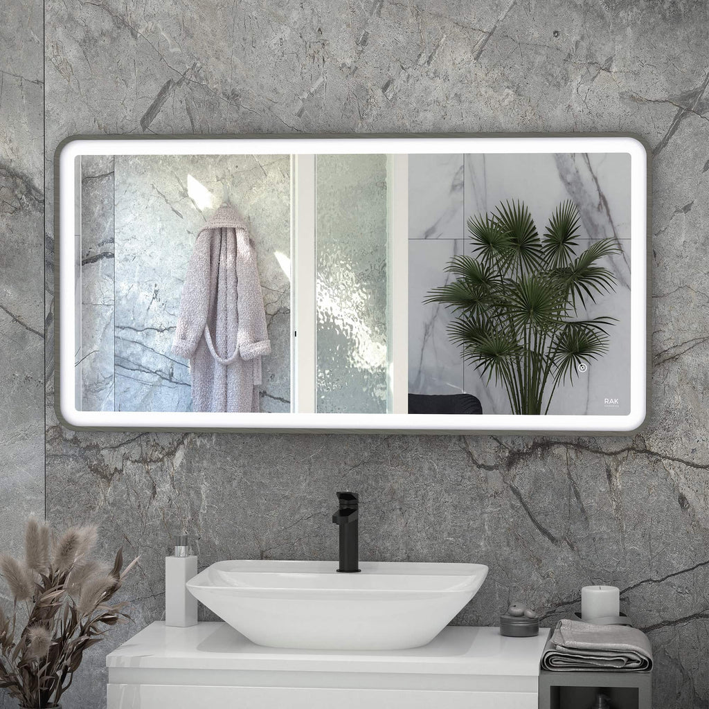 Sleek backlit bathroom mirror above a modern white sink with black tap, featuring a green palm plant and elegant bathroom accessories, showcasing contemporary Bubly Bathrooms interior design.