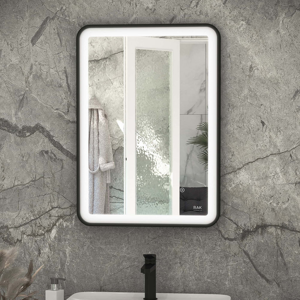 Elegant illuminated bathroom mirror with LED lighting, installed on a textured stone wall, reflecting a modern shower area with frosted glass door and indoor plants, perfect for contemporary bathroom designs.
