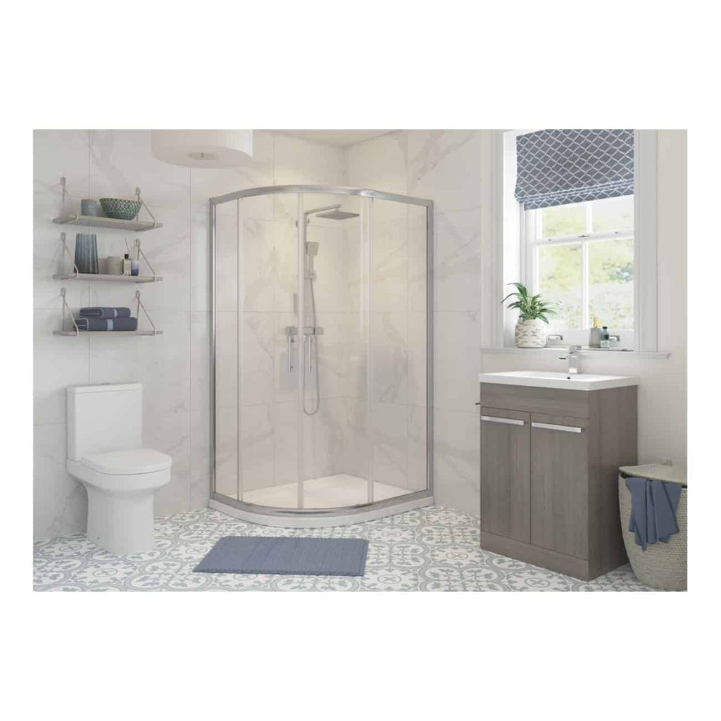 Modern bathroom with shower enclosure, white tiled walls, grey vanity unit, and decorative floor tiles, featuring bath essentials and natural light from a window.