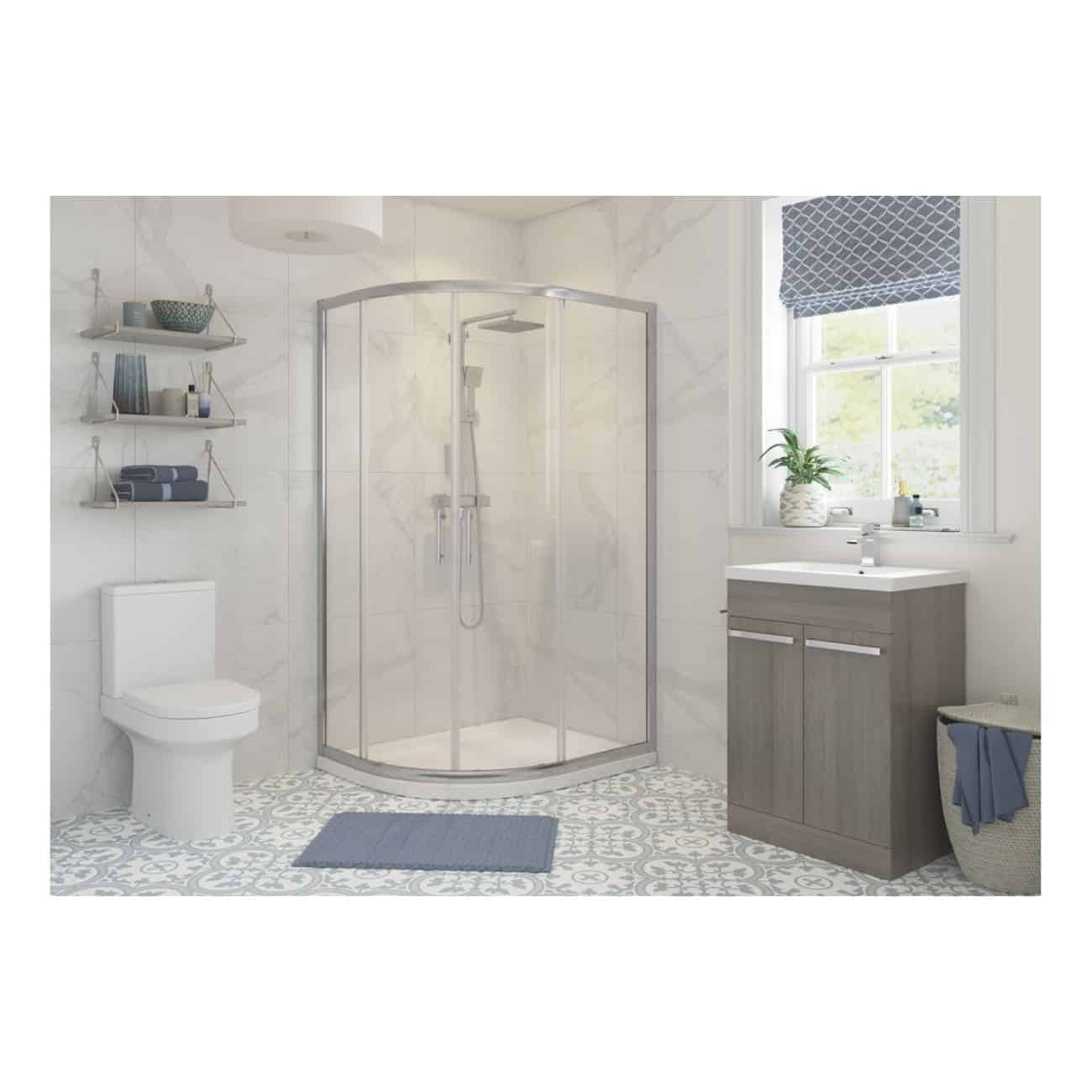 Modern bathroom with shower enclosure, white tiled walls, grey vanity unit, and decorative floor tiles, featuring bath essentials and natural light from a window.